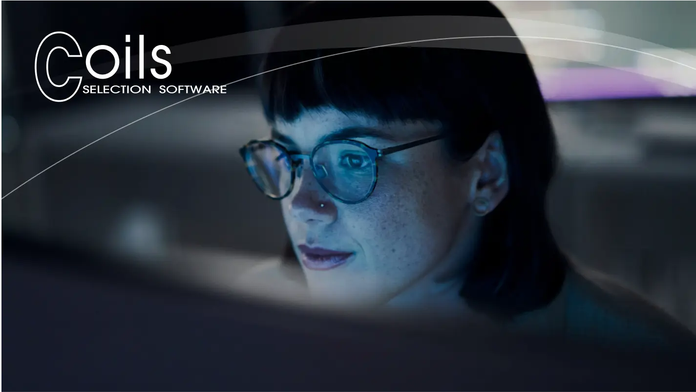 Focused female employee working late at a computer, illuminated by the screen's light
